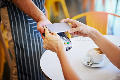 Buy stock photo Shot of an unidentifiable young woman using her smartphone to pay for coffee in a coffee shop