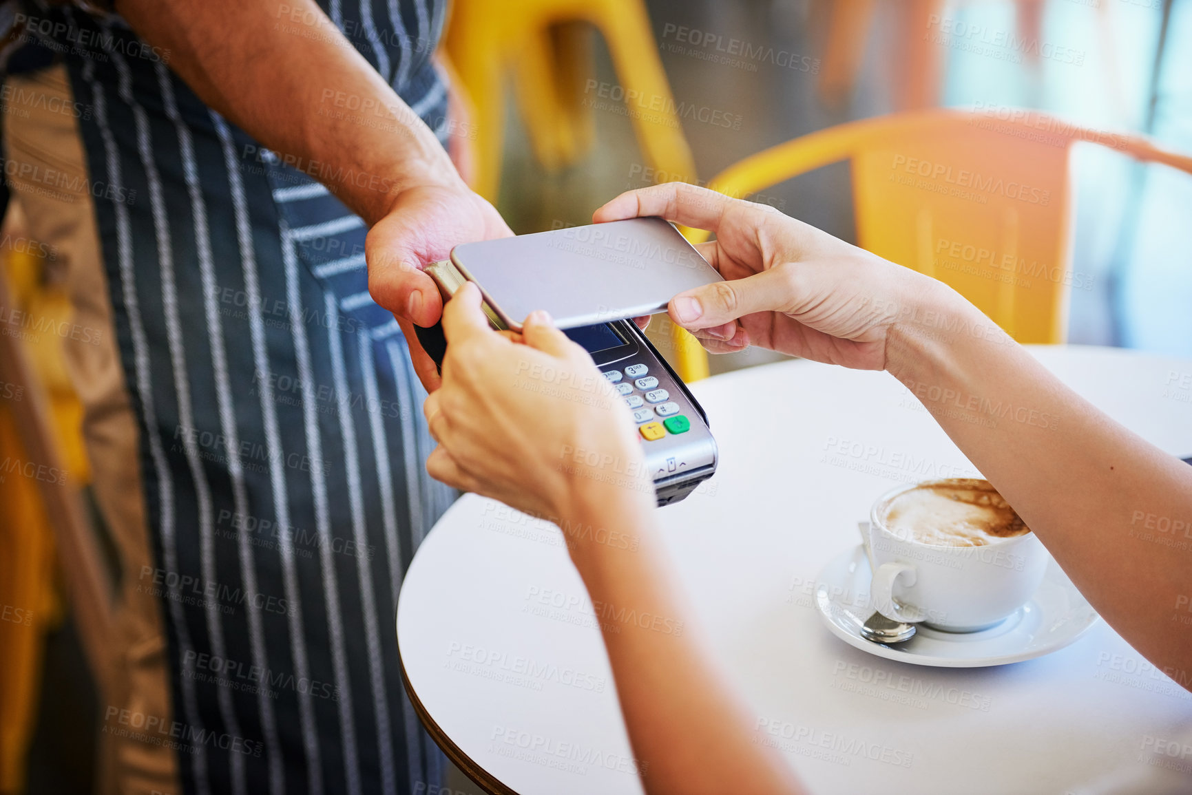Buy stock photo Shot of an unidentifiable young woman using her smartphone to pay for coffee in a coffee shop