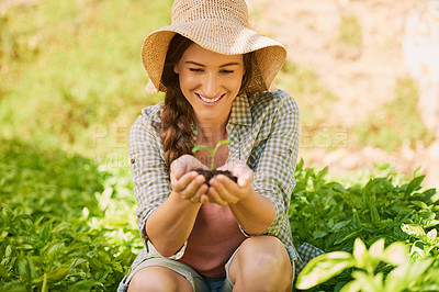 Buy stock photo Shot of a happy young farmer holding a pile of soil with a seedling growing out of it outside