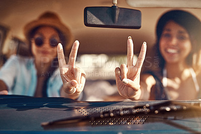 Buy stock photo Shot of two happy friends showing a peace sign on a roadtrip