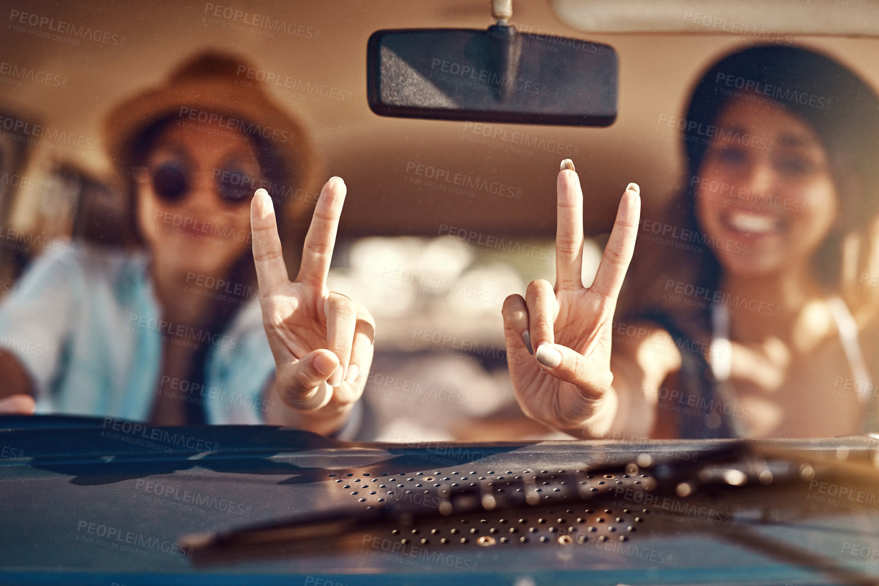 Buy stock photo Shot of two happy friends showing a peace sign on a roadtrip