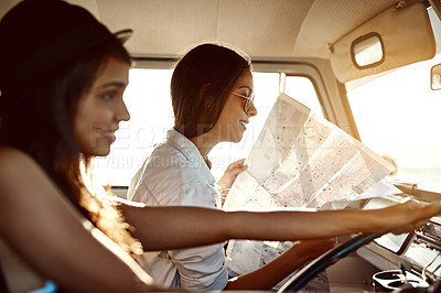 Buy stock photo Shot of two friends reading a map on their road trip