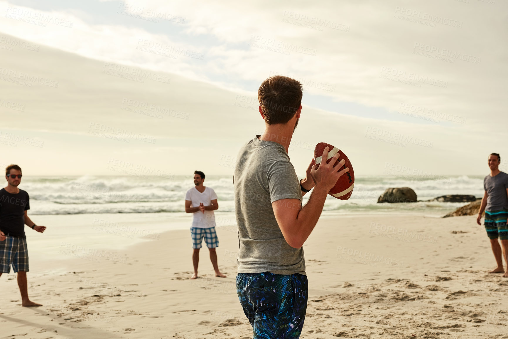 Buy stock photo Holiday, people and men with football by ocean for outdoor game, fun and adventure on weekend. Playful, friends and sports with equipment on sand for beach, activity and vacation in California