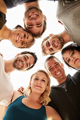 Buy stock photo Low angle portrait of a group of happy friends posing with their arms around each other