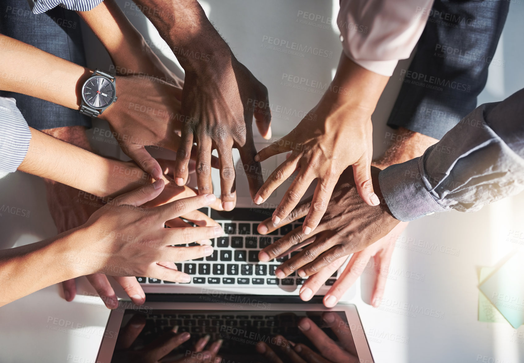 Buy stock photo High angle shot of a group of colleagues posing with their hands over a laptop in the office