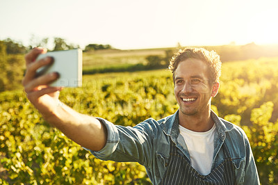 Buy stock photo Shot of a young man taking a selfie with his cellphone while working on a farm