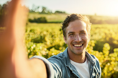 Buy stock photo Shot of a young man taking a selfie while working on a farm