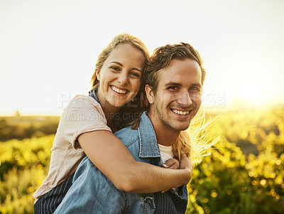 Buy stock photo Shot of a young couple walking through their farm while having a piggyback ride and smiling all the way
