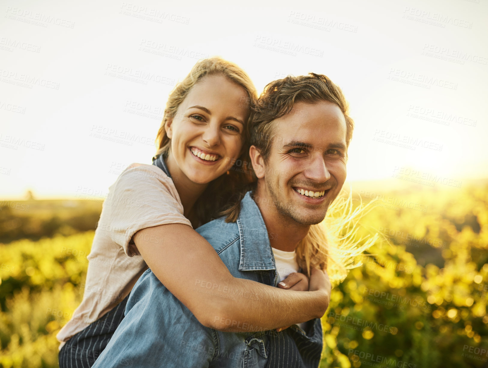 Buy stock photo Shot of a young couple walking through their farm while having a piggyback ride and smiling all the way