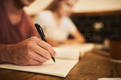 Buy stock photo Cropped shot of two unidentifiable students having a study session at a cafe table