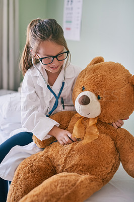 Buy stock photo Shot of a little girl pretending to be a doctor while examining her teddybear