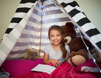 Buy stock photo Portrait of a little girl reading a book with her teddybear in a tent at home