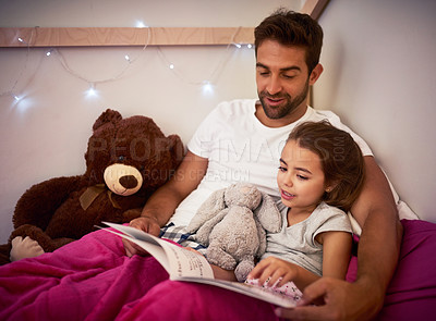 Buy stock photo Cropped shot of a father reading a book with his little daughter in bed at home