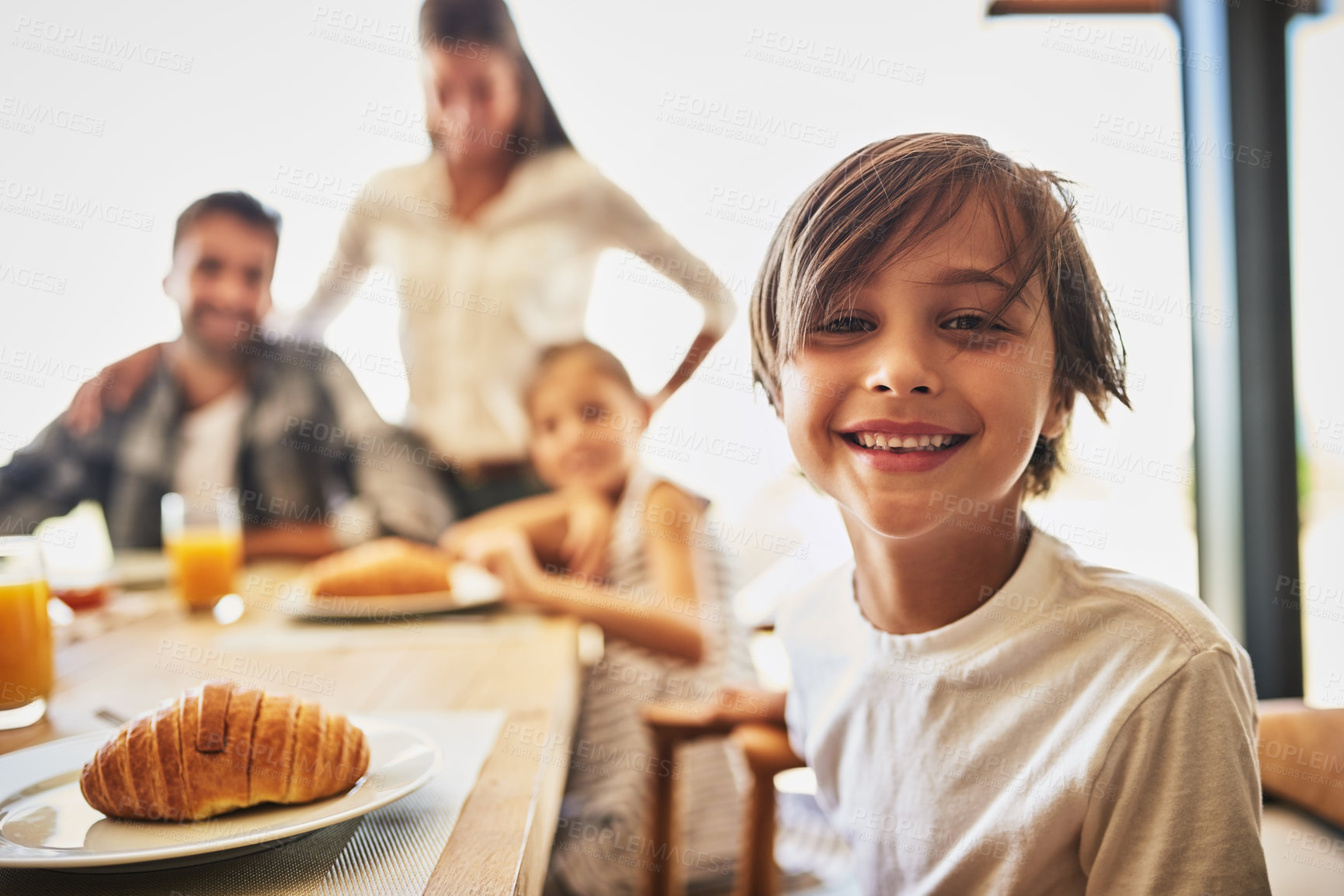 Buy stock photo Portrait of a little boy having breakfast with his family in the background