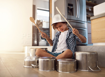 Buy stock photo Shot of a happy little boy playing drums with pots on the kitchen floor while wearing a bowl on his head