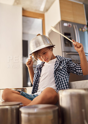 Buy stock photo Shot of a happy little boy playing drums with pots on the kitchen floor while wearing a bowl on his head