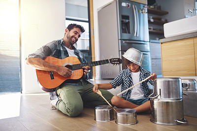 Buy stock photo Shot of a happy father accompanying his young son on the guitar while he drums on a set of cooking pots