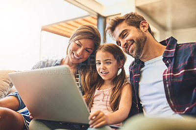 Buy stock photo Shot of a mother and father using a laptop with their daughter on the sofa at home
