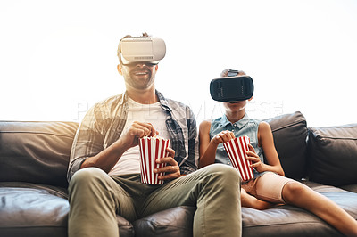 Buy stock photo Shot of a father and daughter eating popcorn and watching movies with virtual reality headsets at home