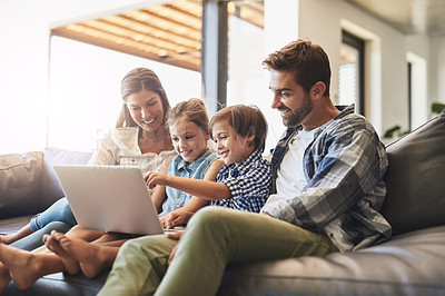 Buy stock photo Shot of a mother and father using a laptop with their son and daughter on the sofa at home