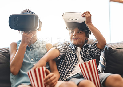 Buy stock photo Shot of a boy stealing his sister’s popcorn while watching movies with virtual reality headsets at home