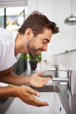 Buy stock photo Close up shot of a handsome man washing his face in the bathroom at home