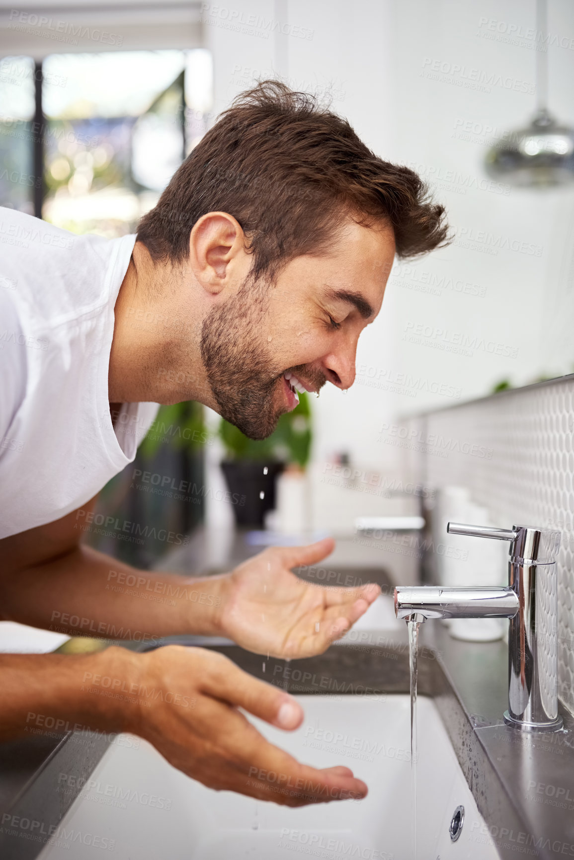 Buy stock photo Close up shot of a handsome man washing his face in the bathroom at home