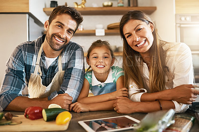 Buy stock photo Portrait of two happy parents and their young daughter trying a new recipe in the kitchen together