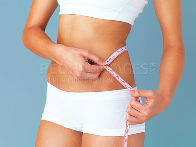 Buy stock photo Woman, measuring tape and lose weight, health and diet with waist size isolated on blue background. Healthy, tummy tuck and body measurement with female person in studio with wellness and fitness