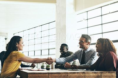 Buy stock photo Shot of two business colleagues shaking hands over the boardroom table during a meeting