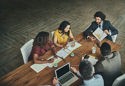 Buy stock photo High angle shot of a team of businesspeople meeting around the boardroom table in the office