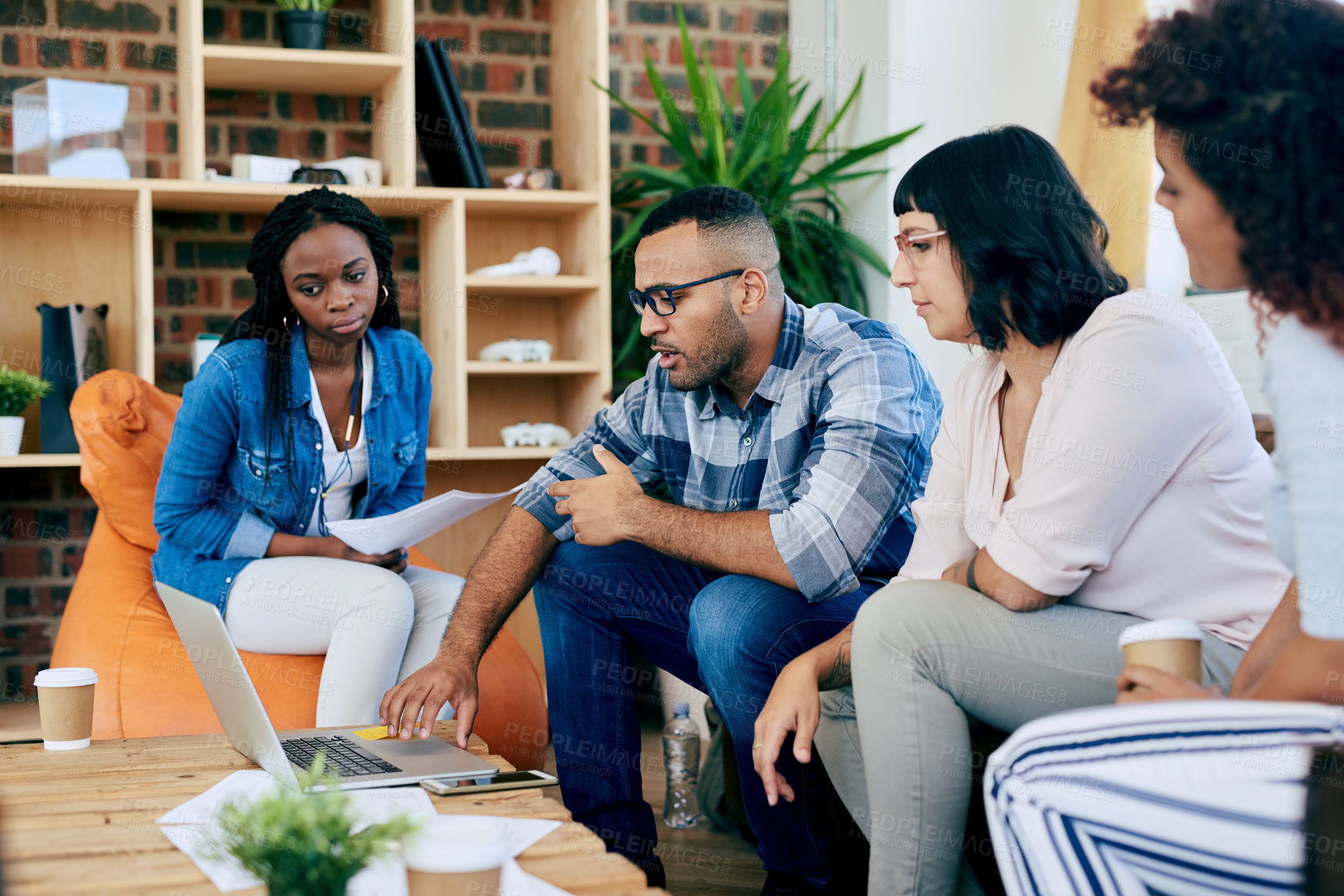 Buy stock photo Shot of a group of colleagues using a laptop together in a modern office