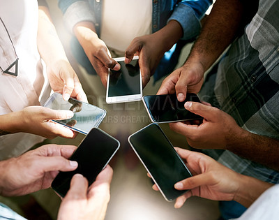 Buy stock photo Cropped shot of a group of colleagues using their cellphone while standing in a circle