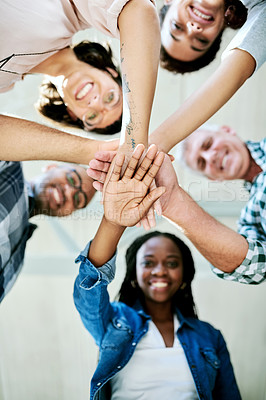 Buy stock photo Shot of a group of creatives stacking their hands in unity