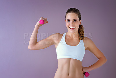 Buy stock photo Studio shot of a healthy young woman holding dumbbells posing against a purple background