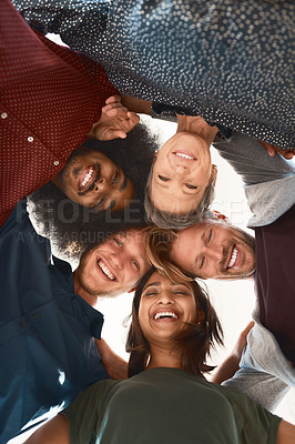 Buy stock photo Low-angle portrait of a team of happy designers posing with their heads in a huddle in the office