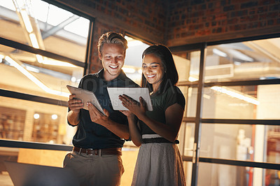 Buy stock photo Shot of two designers using their digital tablets while working nightshift