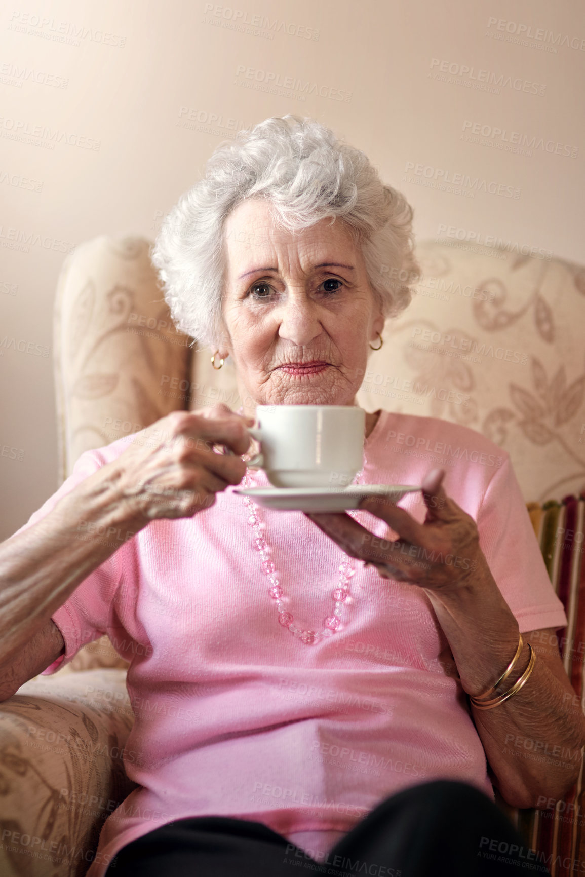 Buy stock photo Portrait of a senior woman having a warm beverage on a chair at home