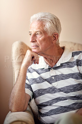 Buy stock photo Shot of a senior man sitting on a chair and looking thoughtful at home