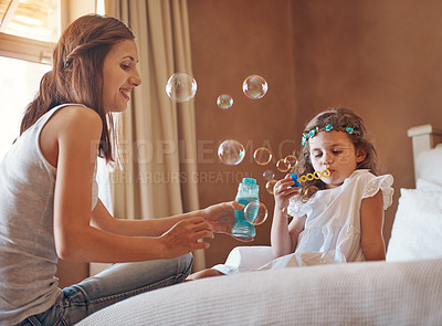 Buy stock photo Mother, girl and blowing bubbles in house for bonding, development and relationship together on bed. Woman, child and playing games in apartment with soap, water and toys for childhood fun activity