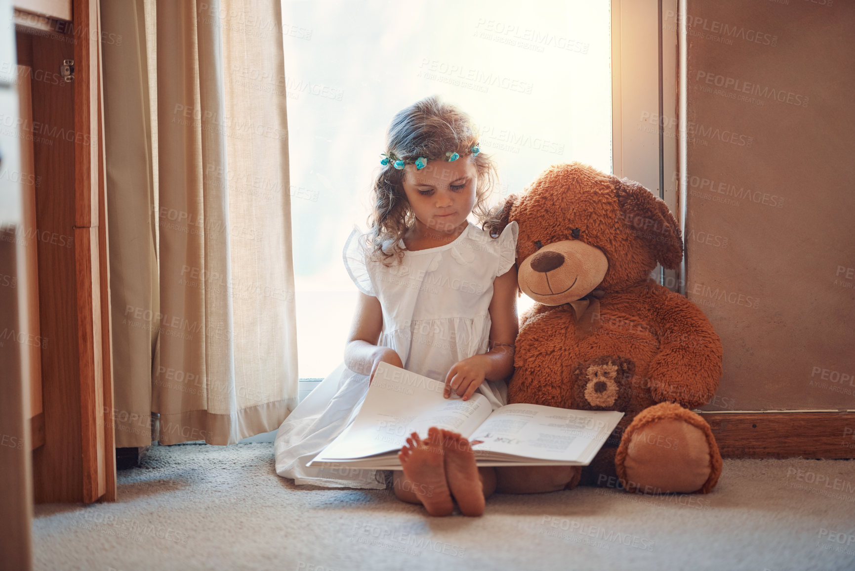 Buy stock photo Shot of an adorable little girl reading a book with her teddybear at home