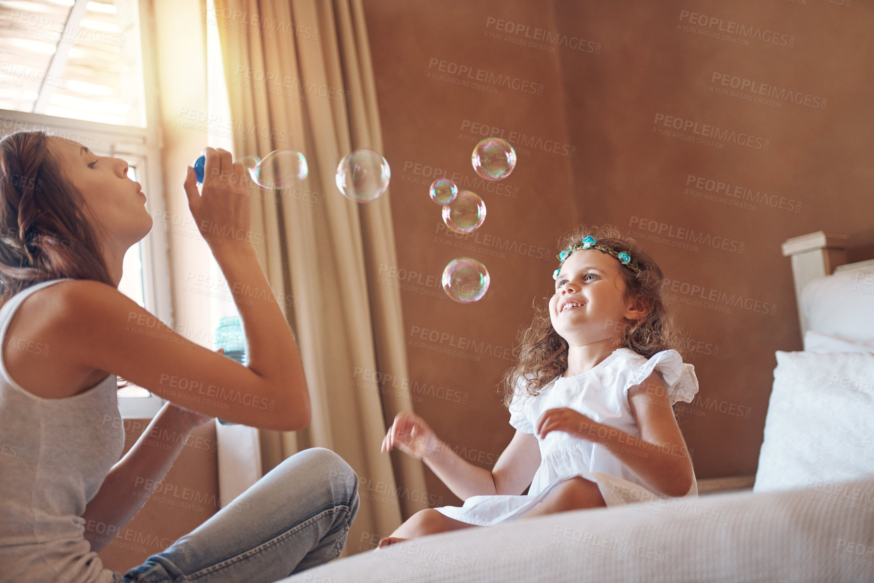 Buy stock photo Mother, girl and blowing bubbles in home for bonding, development and relationship together on bed. Woman, child and playing games in apartment with soap, water and toys for childhood fun activity