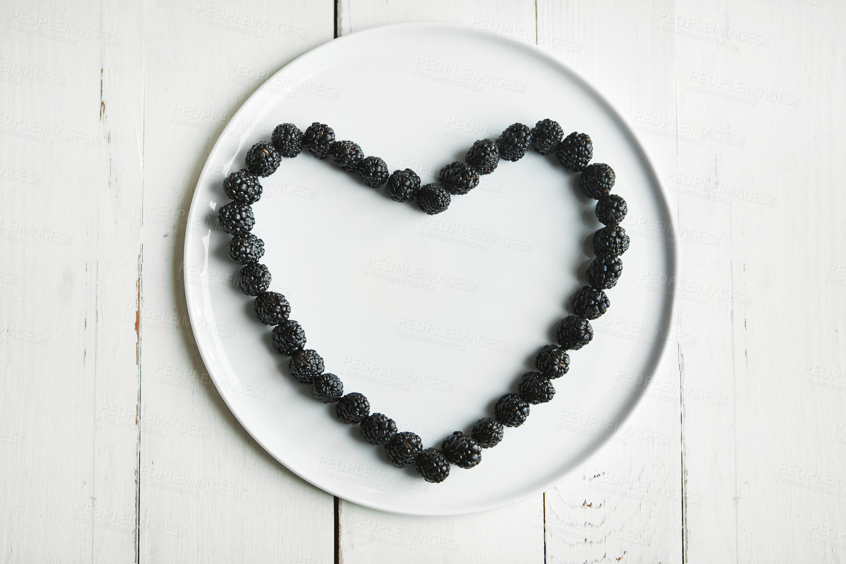 Buy stock photo High angle shot of blackberries in the shape of a heart on a plate