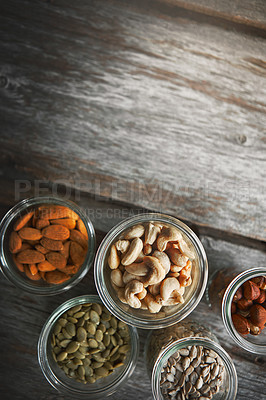 Buy stock photo Nuts, cashew and almond on table, above and mockup space for nutrition, health or promotion for wellness. Hazelnut, sunflower and pumpkin seeds in glass container for meal prep with food at apartment