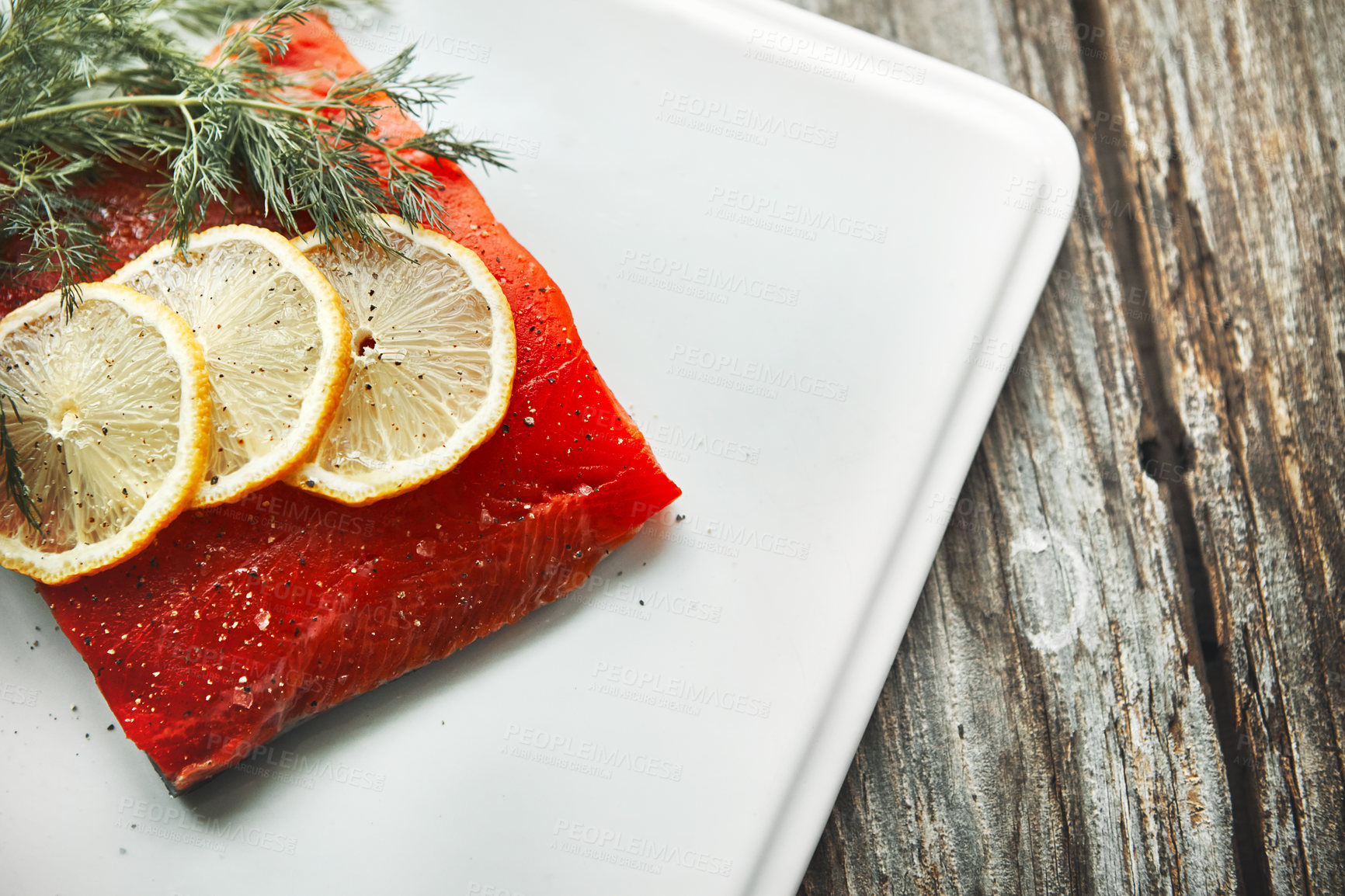 Buy stock photo Shot of a raw piece of meat garnished with slices of lemon