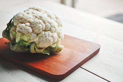 Buy stock photo Cauliflower, wood board and cooking in kitchen for health, lunch and choice for nutrition with wellness. Organic vegetable, cooking and chopping block on table, leaves and meal prep for vegan diet