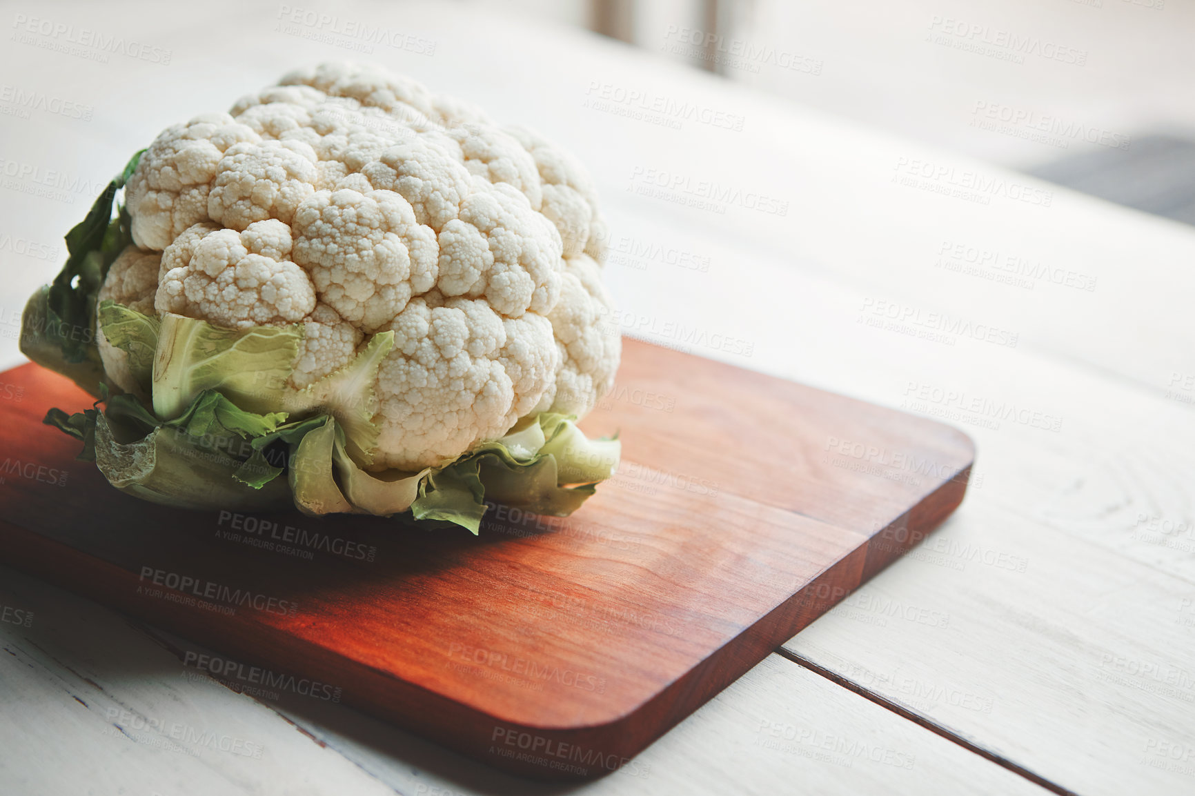 Buy stock photo Cauliflower, wood board and cooking in kitchen for health, lunch and choice for nutrition with wellness. Organic vegetable, cooking and chopping block on table, leaves and meal prep for vegan diet