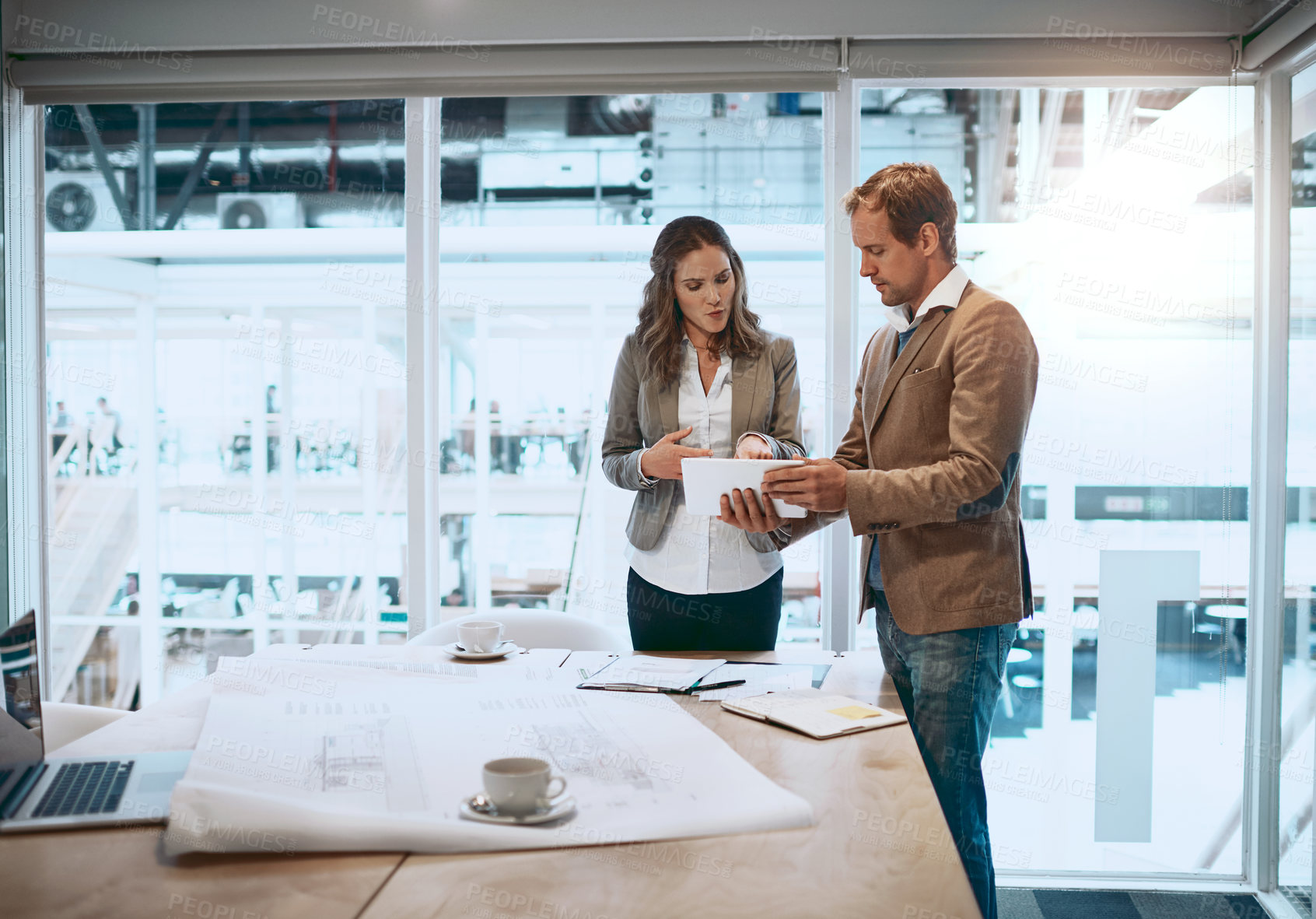 Buy stock photo Cropped shot of two architects looking at a tablet while standing in their office