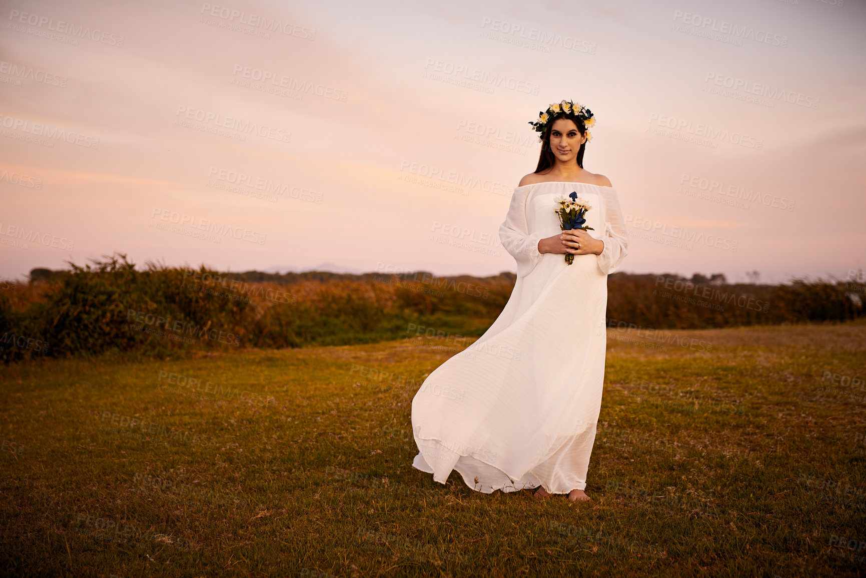 Buy stock photo Shot of a young pregnant woman holding flowers outside