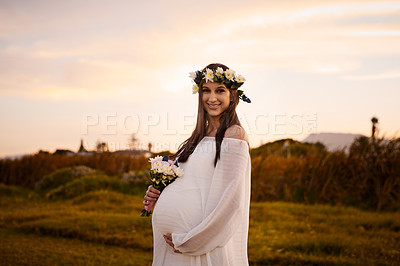 Buy stock photo Shot of a young pregnant woman holding flowers outdoors